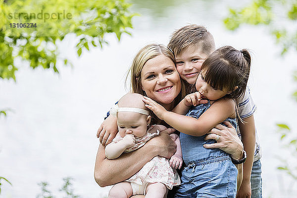 Eine junge Mutter posiert mit ihren Kindern für die Kamera  während sie an einem warmen sonnigen Tag einen Familienausflug in einem Park genießt; Edmonton  Alberta  Kanada