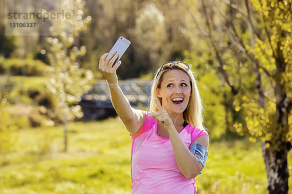 Eine reife Frau  die Sportkleidung und ein Armband für ihr Smartphone trägt  nimmt ein Selbstporträt auf  bevor sie im Herbst zu einem Lauf in einem Stadtpark aufbricht; Edmonton  Alberta  Kanada