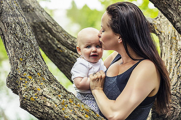 Eine junge Mutter küsst ihre verzweifelte kleine Tochter in einem Park; Edmonton  Alberta  Kanada