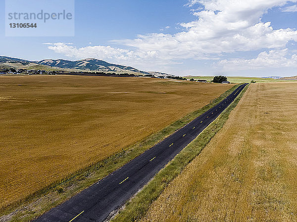 Eine gerade Straße durch die Landschaft mit goldenen Ackerfeldern zu beiden Seiten; Mendon  Utah  Vereinigte Staaten von Amerika