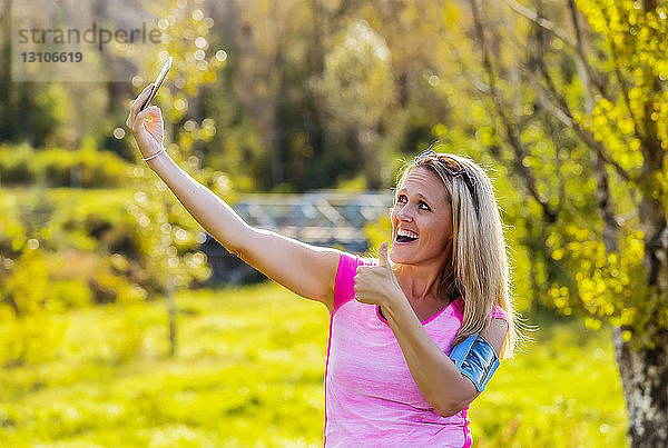 Eine reife Frau  die Sportkleidung und ein Armband für ihr Smartphone trägt  nimmt ein Selbstporträt auf  bevor sie im Herbst zu einem Lauf in einem Stadtpark aufbricht; Edmonton  Alberta  Kanada