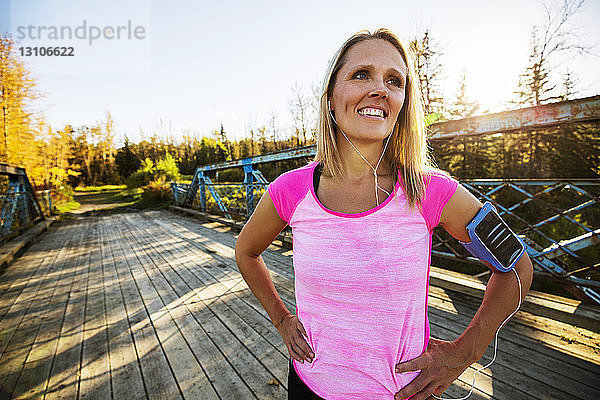 Eine attraktive Frau mittleren Alters  die sich auf einer Brücke ausruht und für die Kamera posiert  nachdem sie an einem schönen  warmen Herbstabend durch einen Stadtpark gelaufen ist und Musik auf ihrem Smartphone gehört hat; Edmonton  Alberta  Kanada