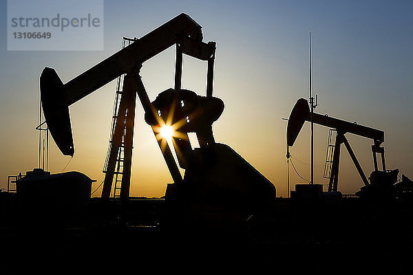 Silhouette eines Pumpjacks mit Sonnenaufgang; Acme  Alberta  Kanada