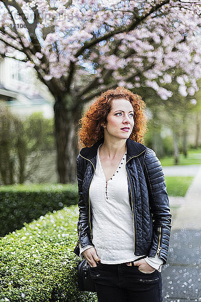 Porträt einer Frau mit rotem  lockigem Haar  die im Frühling im Freien spazieren geht; North Vancouver  British Columbia  Kanada