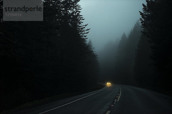 Nebeliger Highway 26 in der Dämmerung mit Scheinwerfern auf einem herannahenden Auto; Oregon  Vereinigte Staaten von Amerika