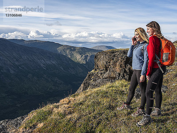 Zwei Frauen benutzen ihre Handys und erkunden die Berge und die Wildnis des Yukon um Haines Junction; Yukon  Kanada