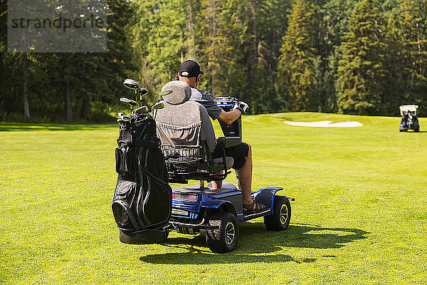 Ein körperlich behinderter Golfer fährt während eines Turniers mit einem speziellen Golfrollstuhl zwischen den Löchern auf einem Golfplatz; Edmonton  Alberta  Kanada