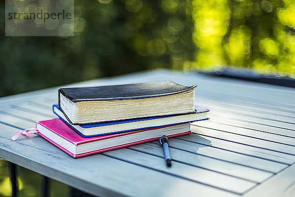 Bibel und Bücher auf einem Tisch gestapelt mit einem Stift im Freien; Surrey  British Columbia  Kanada