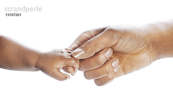 Mutter und Baby reichen sich die Hände auf einem weißen Hintergrund