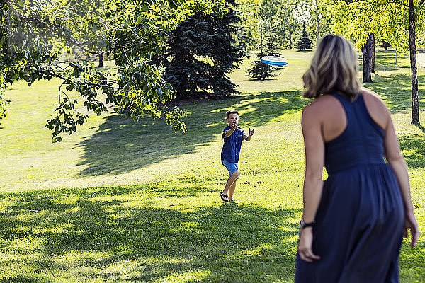 Eine Mutter wirft ihrem Sohn an einem warmen Herbstnachmittag während eines Familienausflugs in einem Park eine Wurfscheibe zu  die er fangen soll; Edmonton  Alberta  Kanada