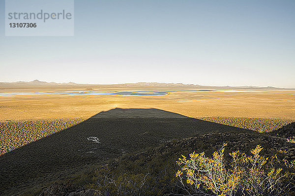 Der Sonnenuntergang hinter einem Vulkan wirft einen langen Schatten auf die Wüste; Malargue  Mendoza  Argentinien