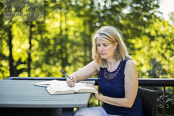 Eine Frau liest ihre Bibel auf ihrer Terrasse; Surrey  British Columbia  Kanada