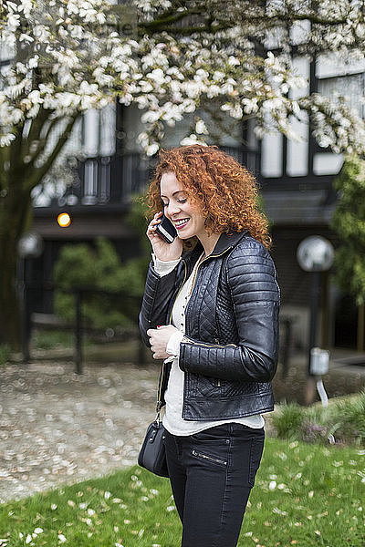 Frau  die im Freien stehend mit einem Handy telefoniert; North Vancouver  British Columbia  Kanada