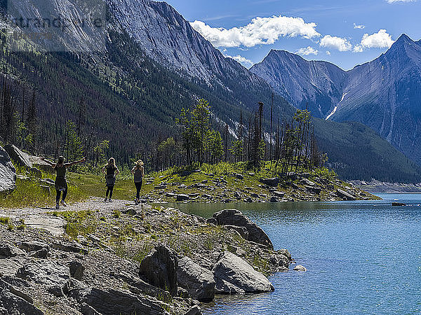 Drei junge Frauen auf einem Weg entlang eines Sees im Jasper National Park; Jasper  Alberta  Kanada