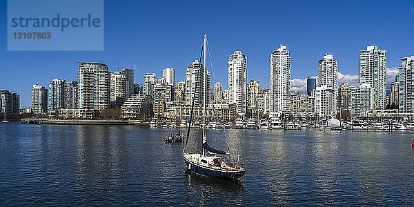 Im Hafen vertäutes Segelboot mit der Skyline von Vancouver entlang der Uferpromenade; Vancouver  British Columbia  Kanada