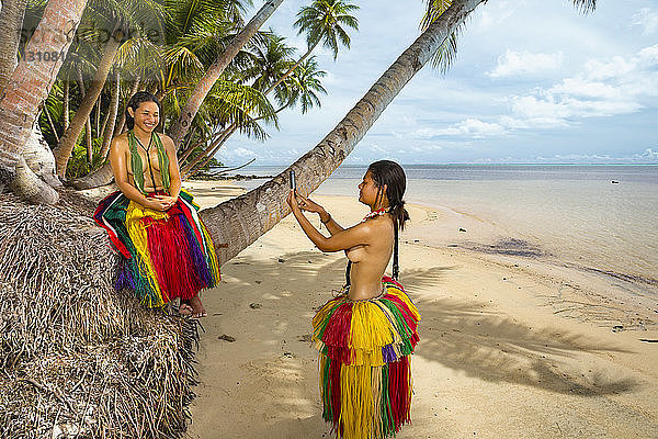 Zwei junge Frauen in traditioneller Kleidung für kulturelle Zeremonien machen ein Foto mit einem Smartphone auf der Insel Yap; Yap  Mikronesien