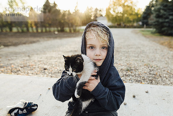 Porträt eines süßen Jungen mit Katze im Park