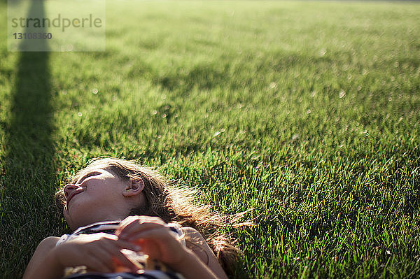 Lächelndes Mädchen auf Grasfeld liegend