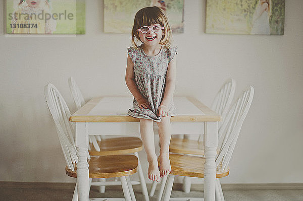 Porträt eines fröhlichen Mädchens  das zu Hause am Esstisch sitzt