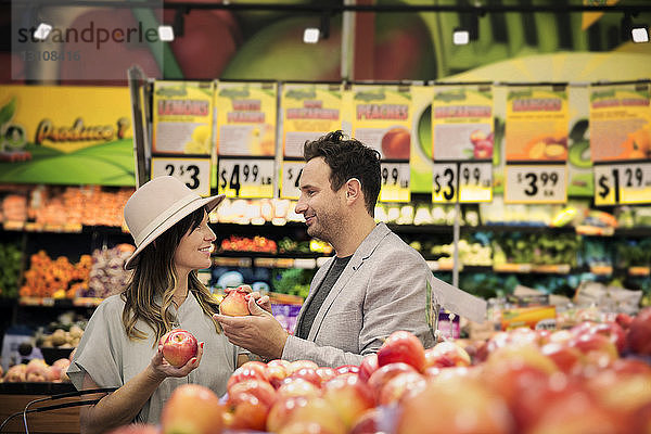 Lächelndes Paar beim Apfeleinkauf im Supermarkt