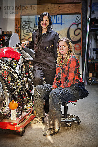 Porträt von selbstbewussten Mechanikerinnen mit dem Fahrrad in der Werkstatt
