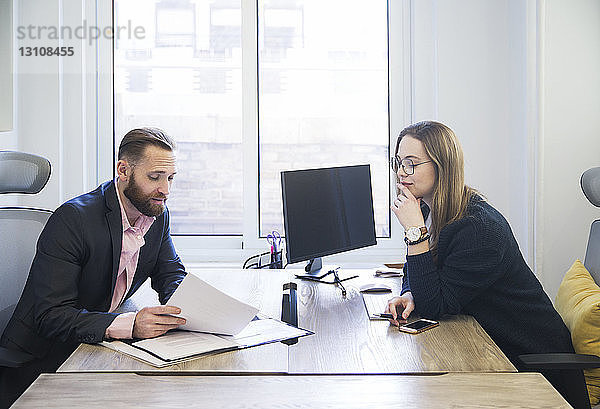 Kollegen diskutieren im Büro über Papierkram