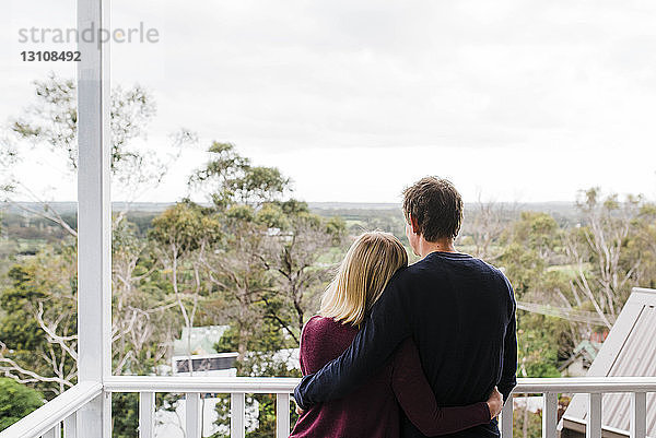 Rückansicht eines auf dem Balkon stehenden Paares mit Armen um die Taille