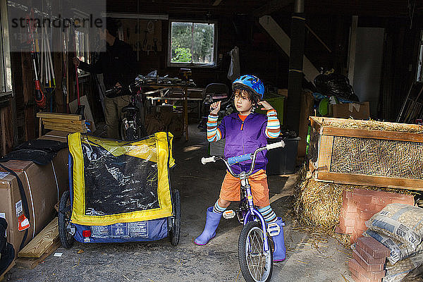 Junge mit Helm  während er mit Fahrrad in der Garage steht