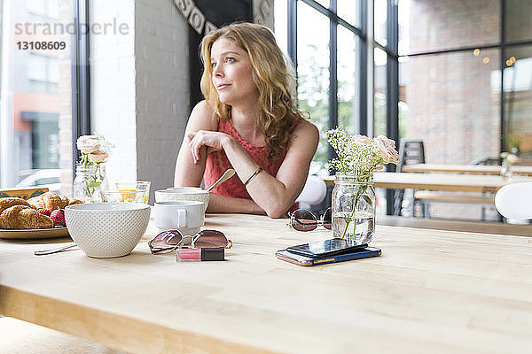 Nachdenkliche Frau schaut weg  während sie im Cafe sitzt