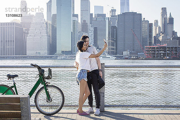 Pärchen  das sich am Handy selbstständig macht  während es an Fahrrädern gegen das Stadtbild steht