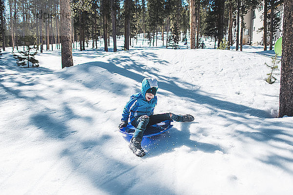 Hochwinkelaufnahme eines Mädchens im Schlitten auf einem schneebedeckten Feld