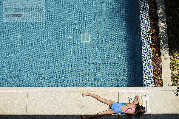 Draufsicht auf ein am Pool liegendes Mädchen