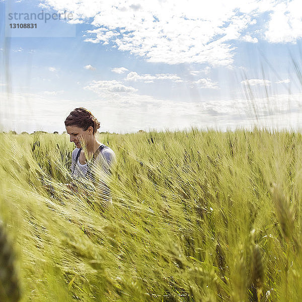 Frau im kultivierten Weizenfeld vor klarem Himmel