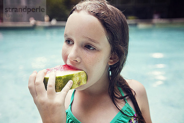 Mädchen isst Wassermelonenscheibe gegen Schwimmbad