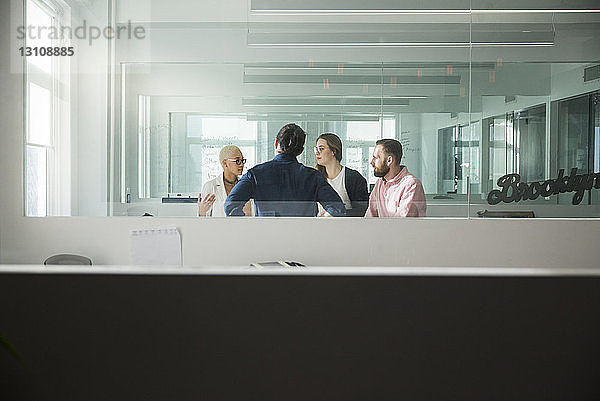 Geschäftsleute  die im Büro diskutieren  durch Fenster gesehen