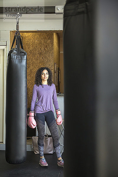 Porträt einer Boxerin  die in einer Turnhalle am Sandsack steht