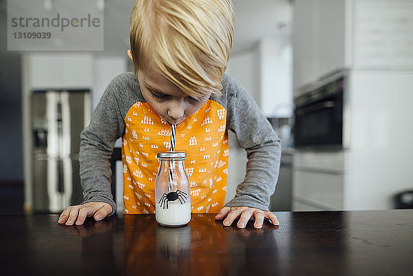 Junge trinkt Milch am Tisch