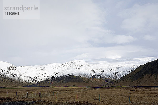 Landschaftliche Ansicht eines schneebedeckten Berges gegen bewölkten Himmel in Island