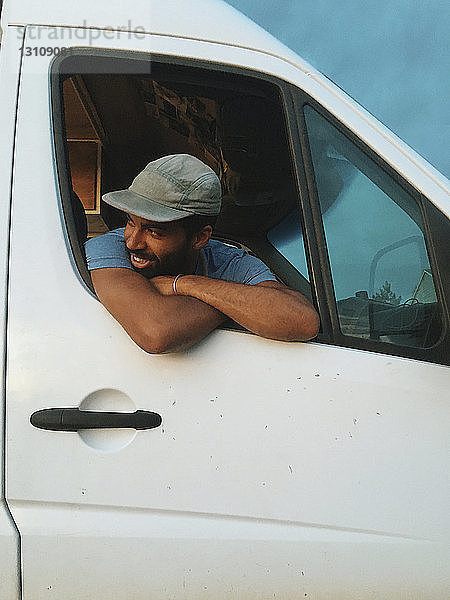 Niedrigwinkelansicht eines Mannes  der durch ein Fenster schaut  während er im Wohnmobil sitzt