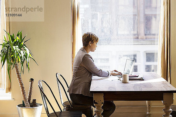Mittlere erwachsene Geschäftsfrau mit Laptop am Schreibtisch im Büro