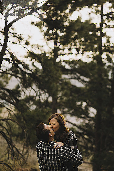 Junges Paar  das sich auf den Mund an Bäumen küsst