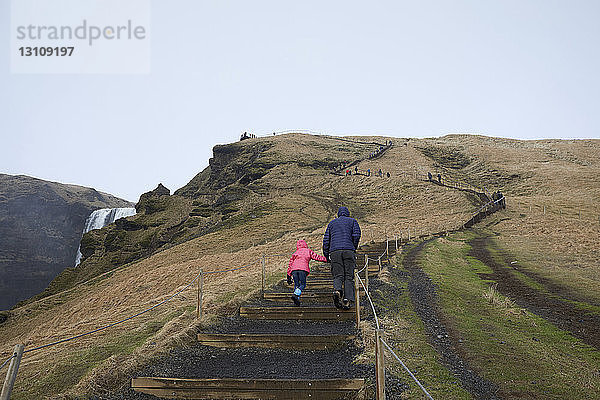 Rückansicht von Vater und Tochter beim Treppensteigen am Berg