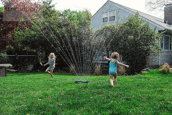 Mädchen spielen mit Wasserspritzen auf dem Rasen