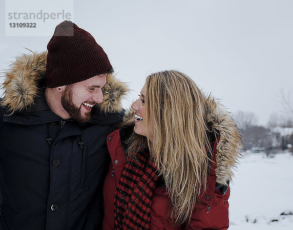 Glückliche Freunde  die sich im Winter gegen den Himmel stellen und einander anschauen