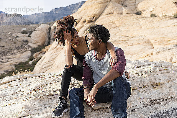 Paar sieht sich an  während es auf einer Felsformation sitzt