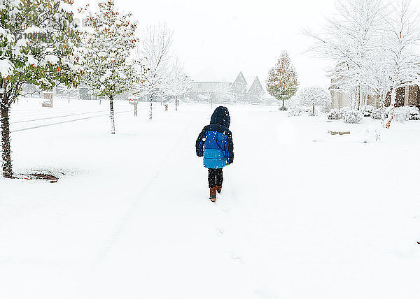 Rückansicht eines Jungen  der auf einem schneebedeckten Feld läuft