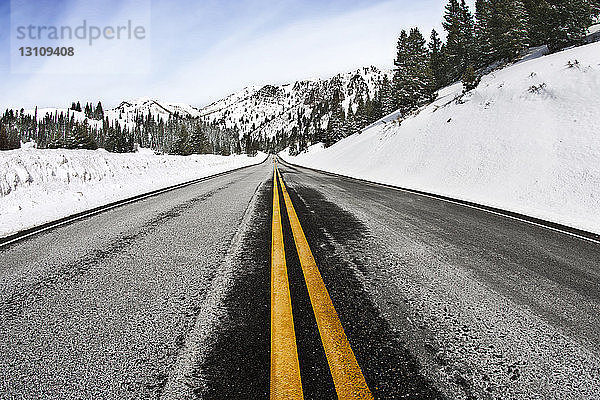 Leere Straße  die zu schneebedeckten Bergen führt