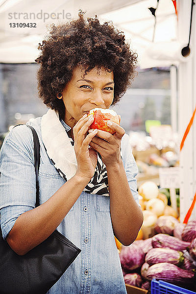 Porträt einer Frau  die einen Apfel auf dem Markt isst