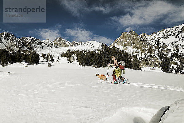 Wanderer mit Hund besteigt schneebedeckten Berg