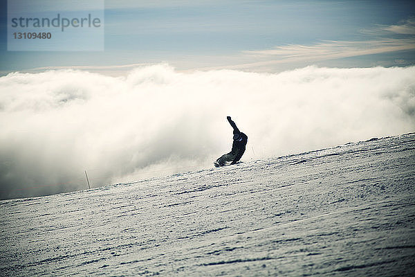 Mann beim Snowboarden auf verschneiter Landschaft bei nebligem Wetter